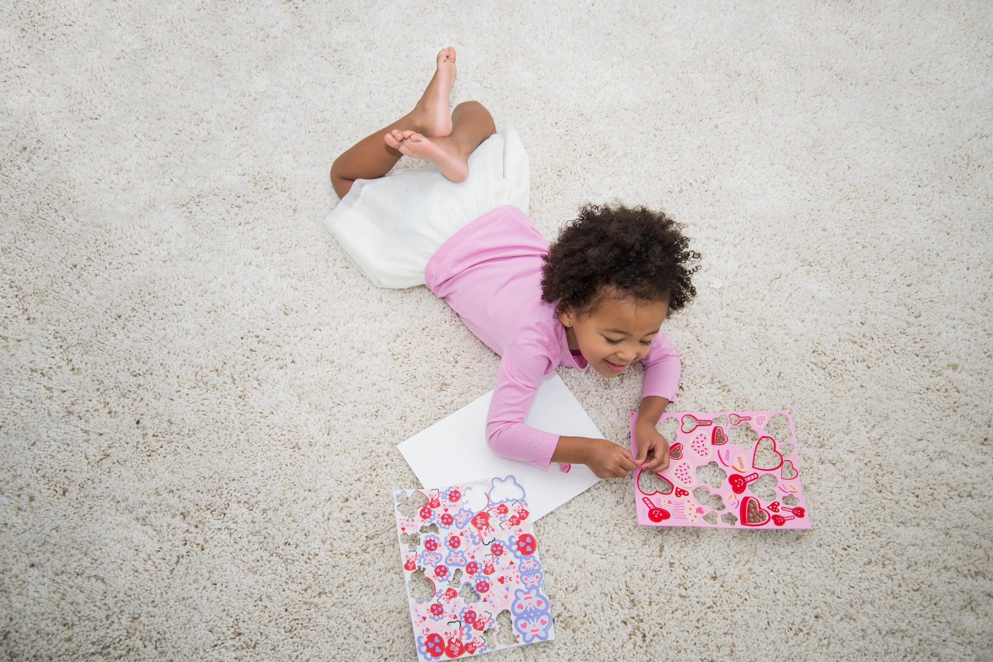 A child lying on the floor making paper valentines